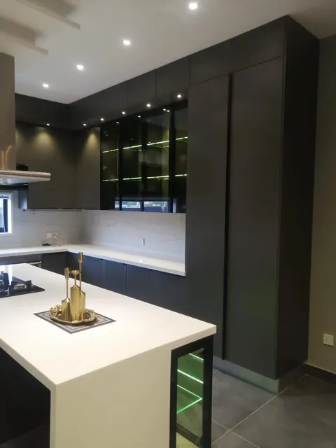 Charcoal kitchen with a white quartz island and glass display units