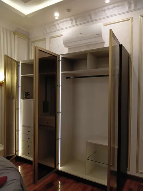 Gold-framed glass door wardrobe with internal LED lighting