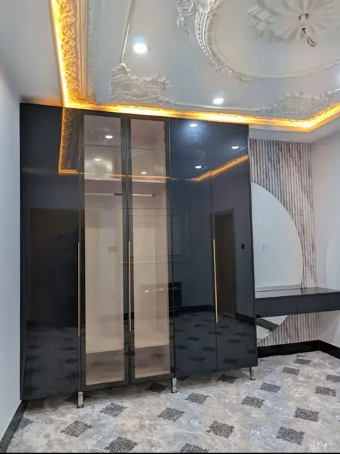 Black gloss wardrobe with glass profile doors and a dressing area under a lit cove ceiling