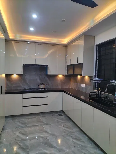 White high-gloss L-shaped kitchen with a black granite countertop
